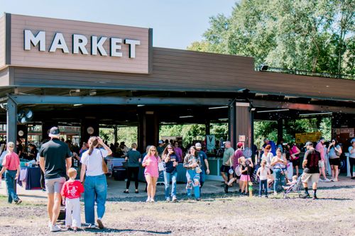 The "MARKET" sign above Market at the Rail District’s entrance, with a crowd of shoppers gathered outside.